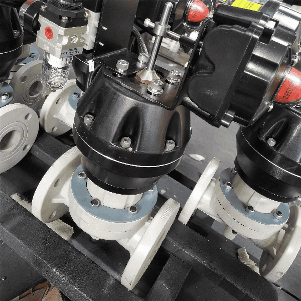 Pneumatic flanged PPH diaphragm valves with black linear actuators assembled on a factory floor for industrial chemical applications